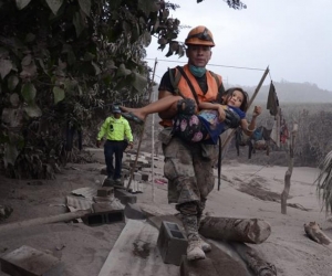 Un trabajador de los equipos de rescate de Guatemala ayuda a una niña en El Rodeo, Escuintla (Guatemala).