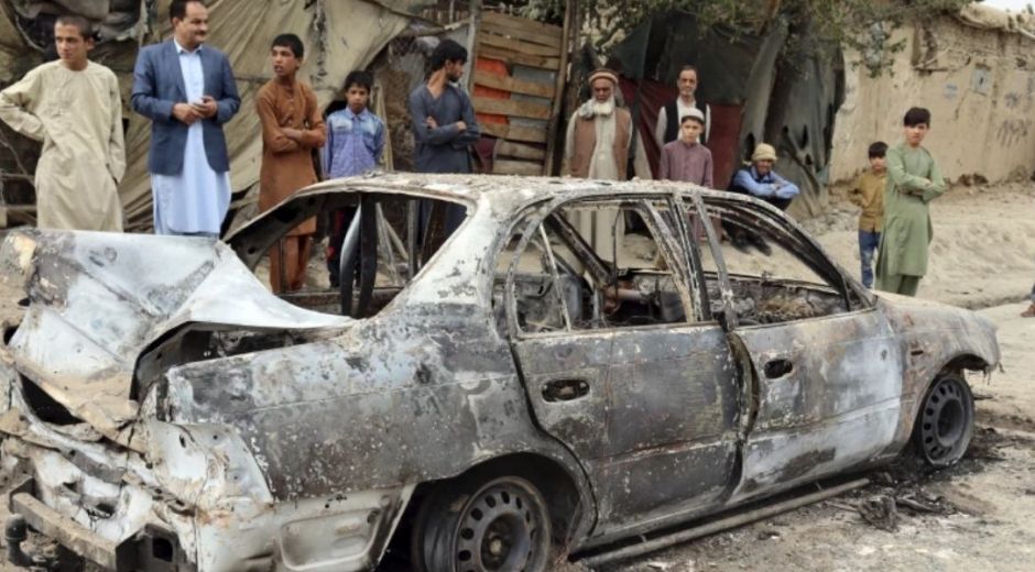 Personas mirando un vehículo dañado por un ataque con un cohete en Kabul, 